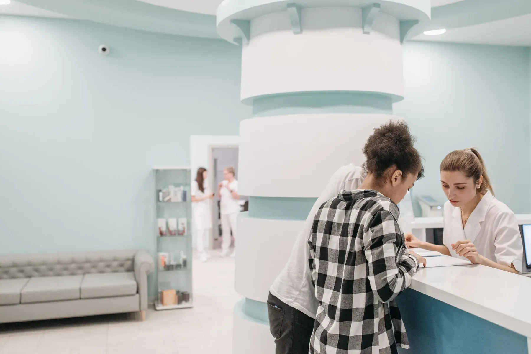 Patients checking in at the reception desk of a bright modern clinic