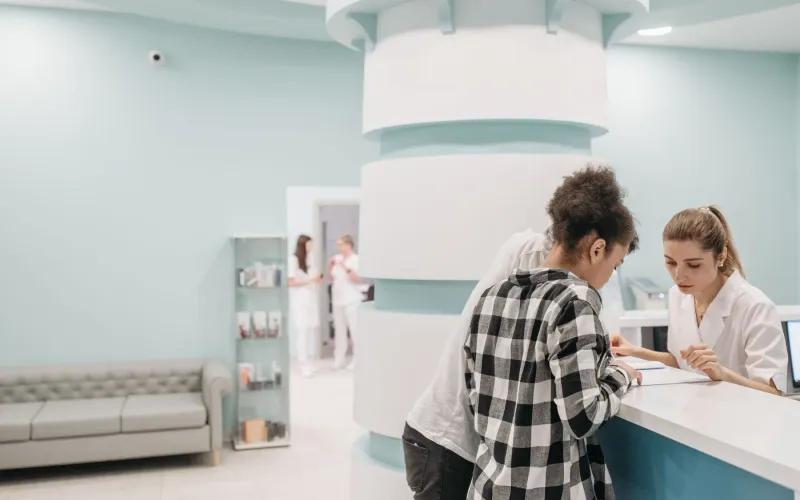 Patients checking in at the reception desk of a bright modern clinic