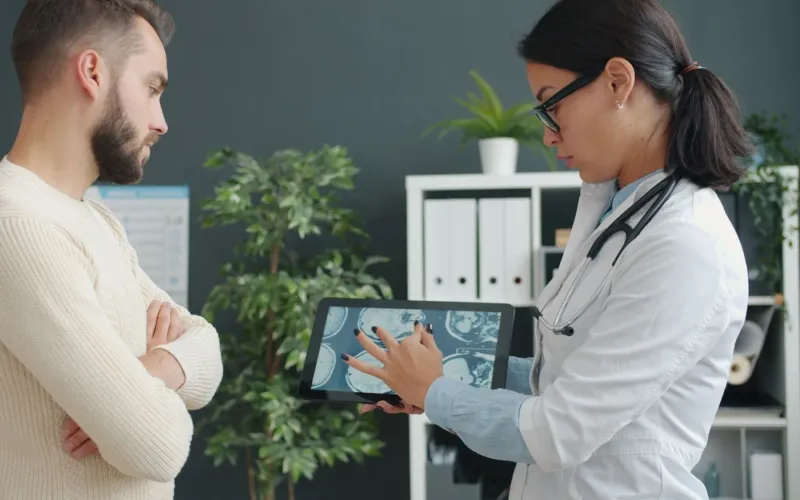 A physician showing a patient a scan on a tablet in a modern consulting room