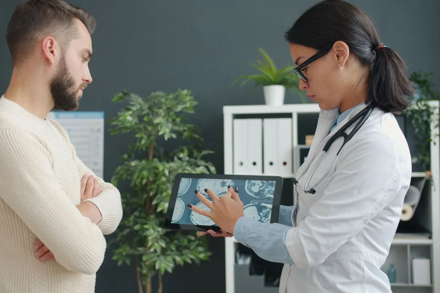 A physician showing a patient a scan on a tablet in a modern consulting room